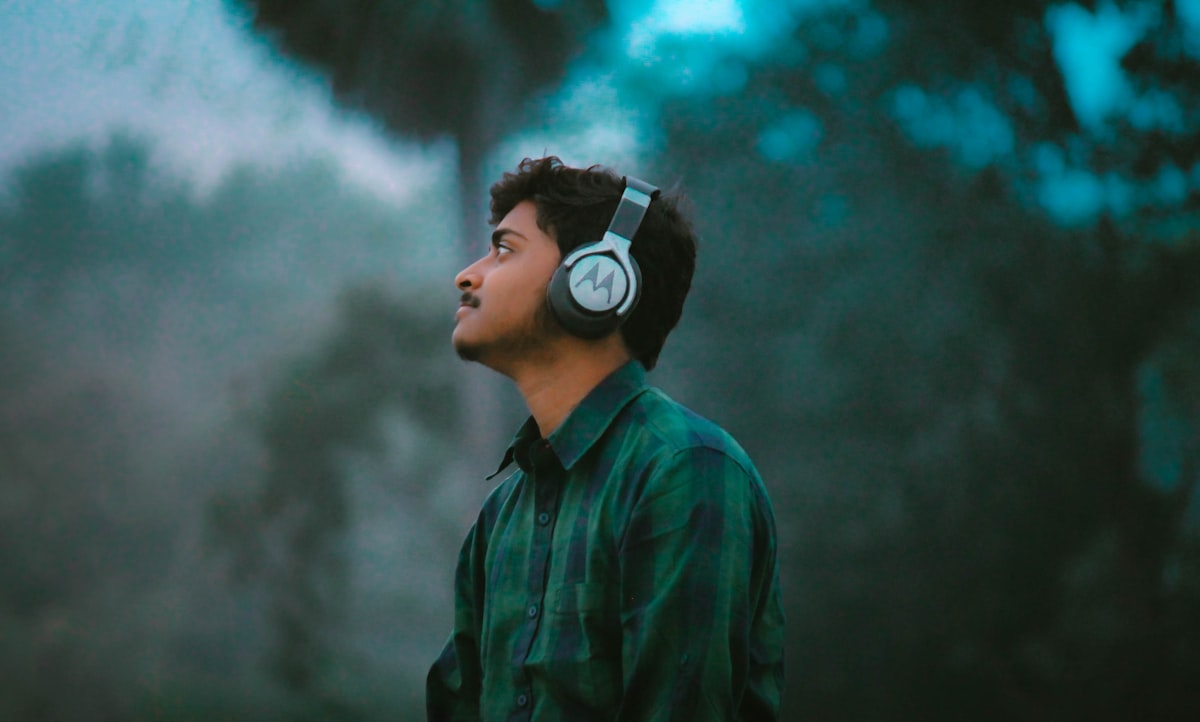 Man in plaid shirt wearing headphones, relaxed and focused